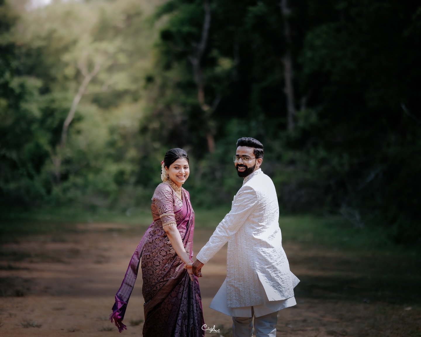 A couple looking back and smiling in a wooded landscape