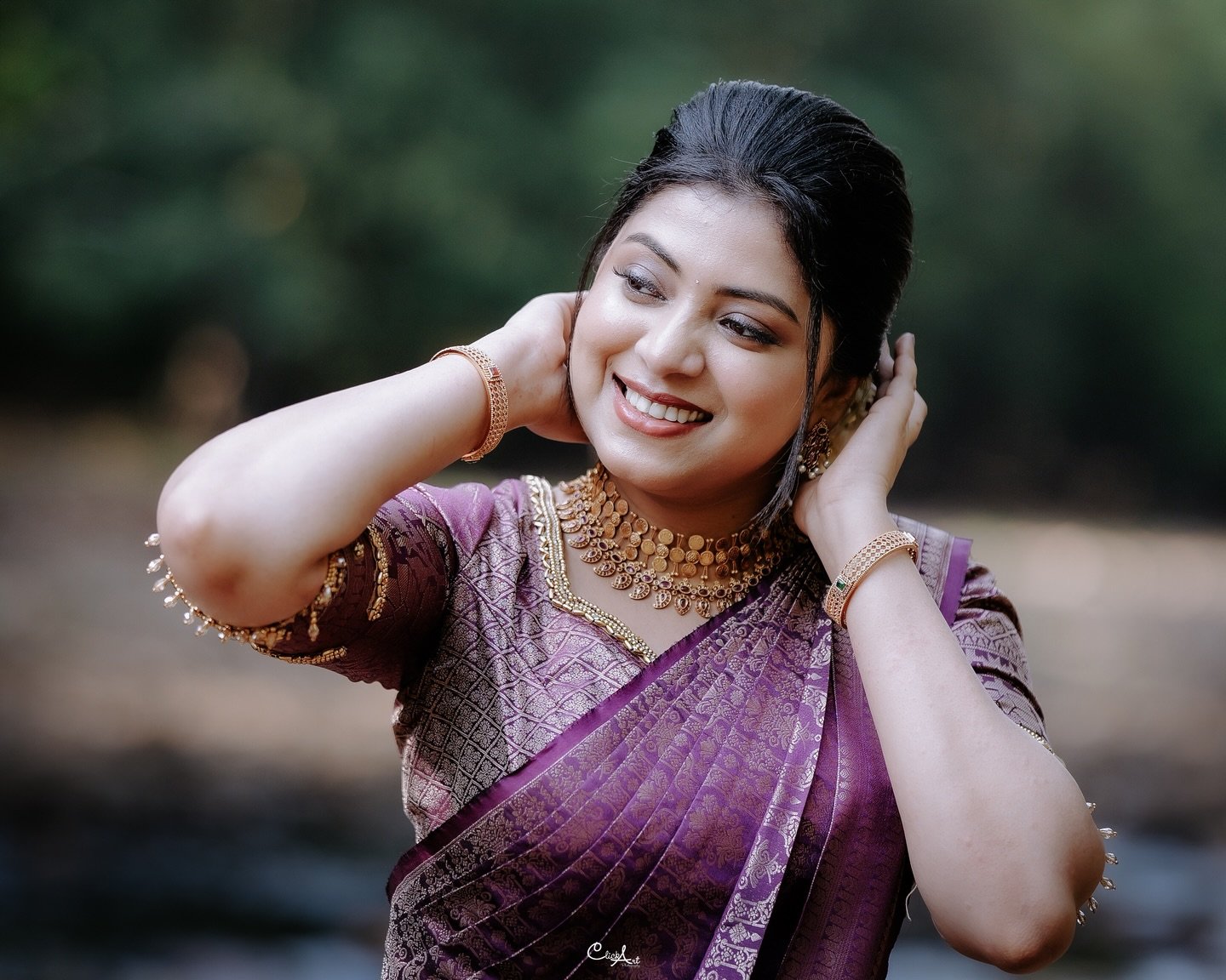 A smiling bride in a purple sari and traditional jewellery